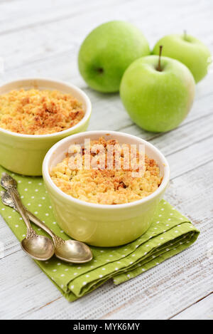 Apple crumble in small baking dish with fresh apples on wooden background Stock Photo