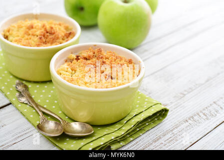 Apple crumble in small baking dish with fresh apples on wooden background Stock Photo