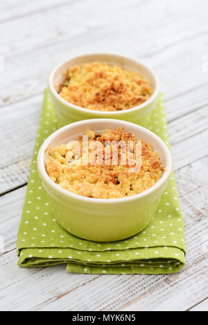 Apple crumble in small baking dish with fresh apples on wooden background Stock Photo