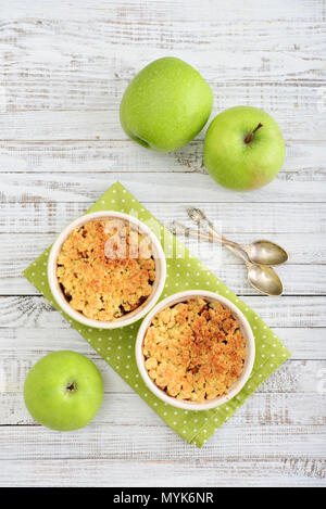 Apple crumble in small baking dish with fresh apples on wooden background Stock Photo