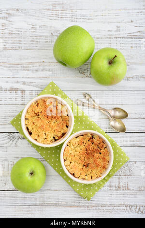 Apple crumble in small baking dish with fresh apples on wooden background Stock Photo