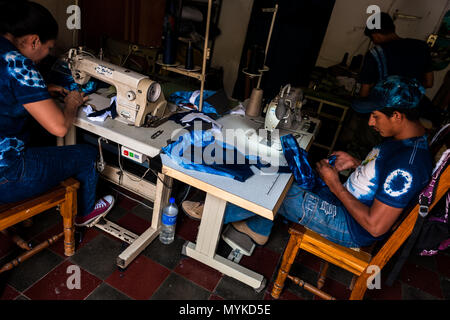 A Salvadoran seamster sews an indigo-dyed tote bag on the sewing machine in an artisanal clothing workshop in Santiago Nonualco, El Salvador. Stock Photo