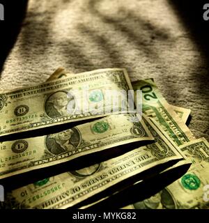 Stacks of dollar bills arranged on a soft surface in warm, natural light during the afternoon Stock Photo