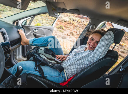 Young woman sits relaxed in her car and smiles, holiday, Tenerife, Canary Islands, Spain Stock Photo