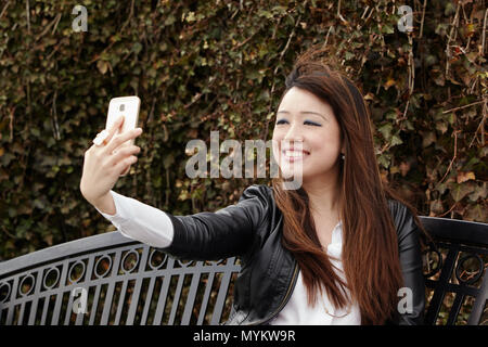 asian woman using cellphone outside Stock Photo