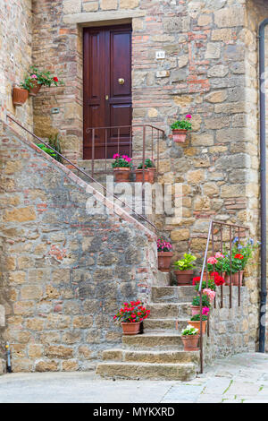 pots of colourful flowers outside stone house up stairs in medieval village town of Monticchiello, near Pienza, Tuscany,  Italy in May Stock Photo