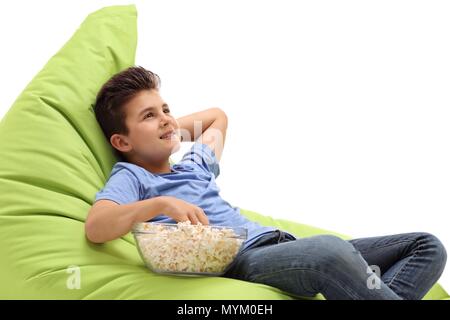 Little boy sitting on a beanbag and eating popcorn isolated on white background Stock Photo