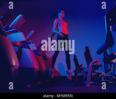 Slim woman jumping between rows of exercise machines Stock Photo