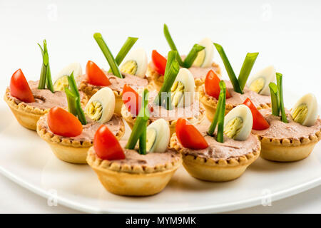 Three baguette slices with liver and apple pate and a thin tomato slice on top. Shallow DOF Stock Photo