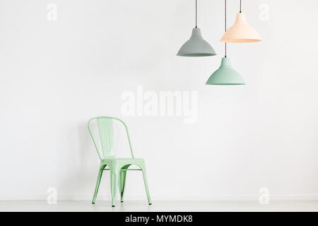 Pastel lamps above mint chair in empty room with copy space on white wall Stock Photo