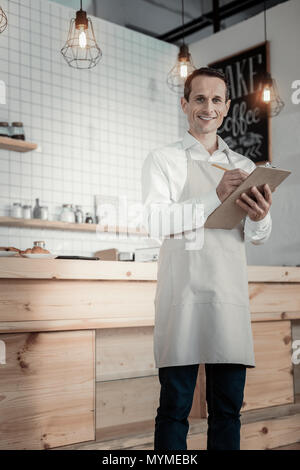 owner of a new business is taking notes in a notebook while sitting on ...