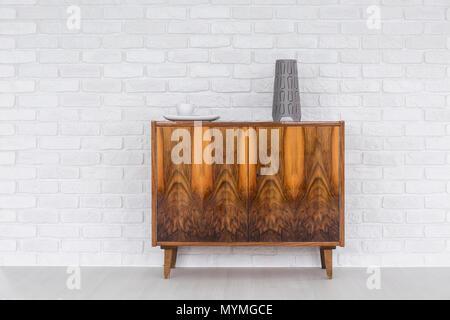 Old, wood commode standing in light interior with brick wall texture Stock Photo