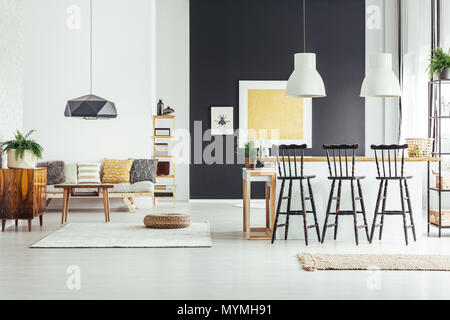 Black bar stools at countertop of kitchen island in spacious interior with pouf on white carpet Stock Photo