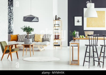 Bar stool at kitchen countertop in multifunctional interior with green chair and sofa Stock Photo