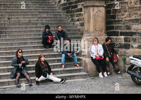 Prague, September 21, 2017: The company of Asian tourists is tired after the tour and rests on the stairs Stock Photo