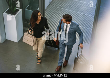 Businessman and woman walking together with baggage and talking. Business people arriving for conference. Stock Photo