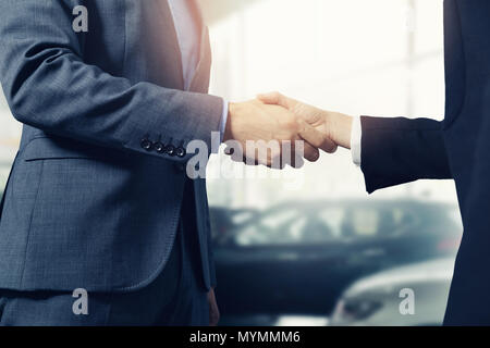 salesman and customer handshake after successful deal in car dealership Stock Photo