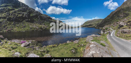 People walking along the scenic road of Gap of Dunloe, a narrow mountain pass in county Kerry, Ireland, with Augher lake in the background. Stock Photo