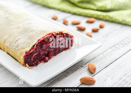 Cherry strudel with almond and powdered sugar on wooden background Stock Photo