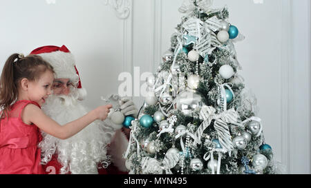 Santa Claus with pretty little girl decorating Christmas tree Stock Photo