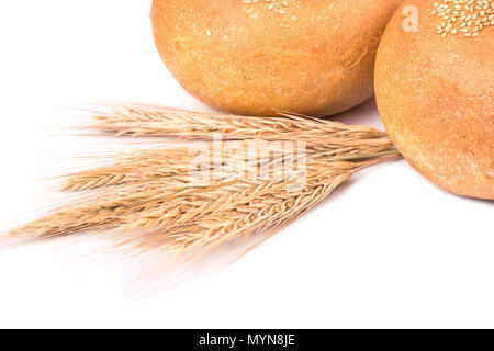Two lush buns with sesame seeds and spikelets of wheat on a white background Stock Photo