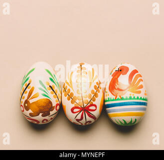 Three handmade Easter eggs on creamy background. Folk traditions. Slavic holiday. Stock Photo