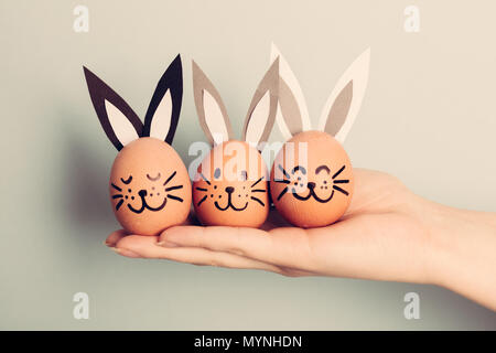 Three little Easter bunnies made from an egg held by woman's hand. Christianity traditions. Easter egg. Stock Photo
