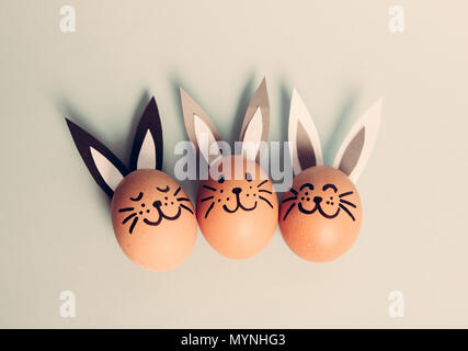 Three smiling bunnies laying on the floor. Egg decoration. Easter symbols. Stock Photo