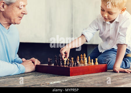 Little boy sitting on the table while playing chess Stock Photo