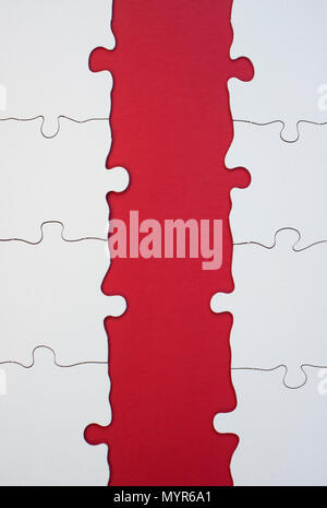 Detail of an incomplete all-white jigsaw puzzle on a red background Stock Photo