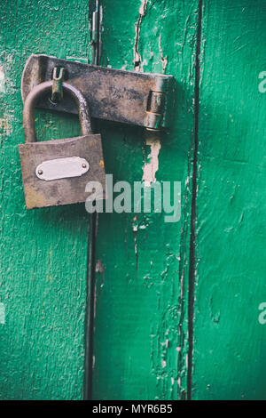Locked rusty padlock on a weathered green shed door Stock Photo