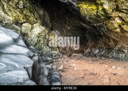 A shaft of light  shines through Merlin's Cave at low tide. The cave is located underneath Tintagel Castle in North Cornwall and was made famous by Te Stock Photo