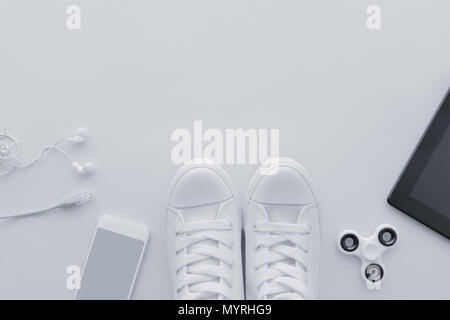 Millennial generation gadgets flat lay top view with copy space - minimalistic composition in pale white pastel tones including smartphone with earpho Stock Photo