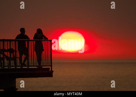 Aberystwyth Wales UK, Thursday 07 June 2018  UK Weather: The very hot sunny summer  sunshine continues, with the day ending in a glorious sunset over people standing pn the seaside pier in Aberystwyth on the Cardigan Bay coast of west Wales   photo © Keith Morris / Alamy Live News Stock Photo
