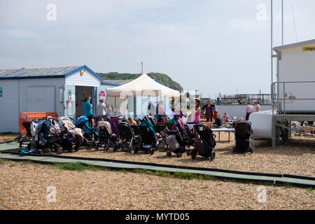 Hastings, East Sussex, UK. 8th Jun, 2018. UK Weather: Sunny but windy in Hastings this morning. This mum and baby group line up their pushchairs as they let the toddlers play on the sand. © Paul Lawrenson 2018, Photo Credit: Paul Lawrenson / Alamy Live News Stock Photo