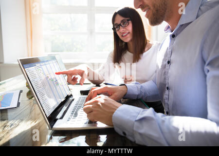 Two Young Businesspeople Analyzing Gantt Chart On Laptop Stock Photo