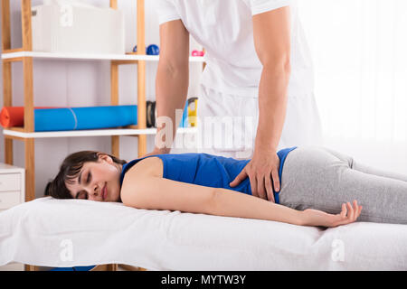 Physiotherapist's Hand Giving Back Massage To Relaxed Young Woman Stock Photo