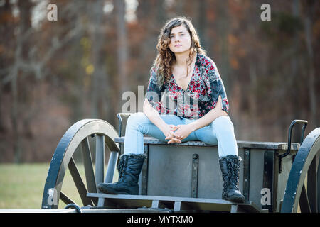 Young woman sitting manspreading womanspreading spreading legs on old cannon carriage in Manassas National Battlefield Park in Virginia where Bull Run Stock Photo