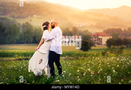 Couple kissing in the field with romantic sunset view Stock Photo