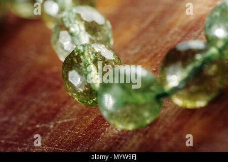 Natural green jade nephrite stones beads on wooden surface. Green grassy color round stone beads macro image Stock Photo