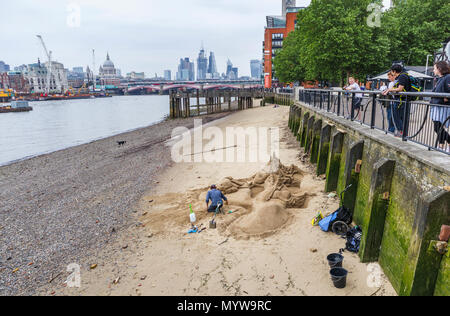 Sand sculptor working on a sculpture on a beach at low tide on the River Thames, South Bank Embankment riverside walkvnear Oxo Tower Wharf, London SE1 Stock Photo