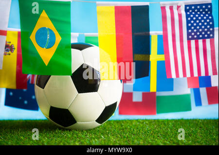 International world flag bunting hanging around a football sitting on grass Stock Photo