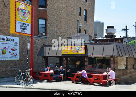 People enjoy Chicago style hotdogs at sidewalk picnic tables outside ...