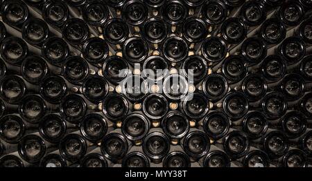 Old dusty wine bottles stored for aging. Stock Photo