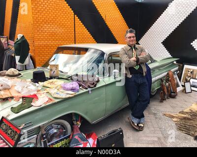 Stable St, London, UK. 23rd Apr, 2017. A trader lined up next to a vintage car at the Classic Car Boot Sale in Granary Square, Kings Cross, London, England, UK. Sunday 23rd April 2017. Credit: Jamie Gladden/StockimoNews/Alamy Live News Stock Photo