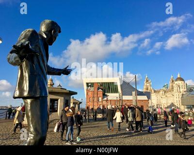 UK Weather: Sunny in Liverpool. Families enjoying sunny but cold day at Albert Dock in Liverpool with Billy Fury statue in foreground Stock Photo