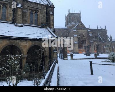 UK Weather: Sherborne, Dorset. Snow falls on St Johns Almshouse and the historic Sherborne Abbey as the so called mini Beast from the East brings another icy blast to the South West. Stock Photo