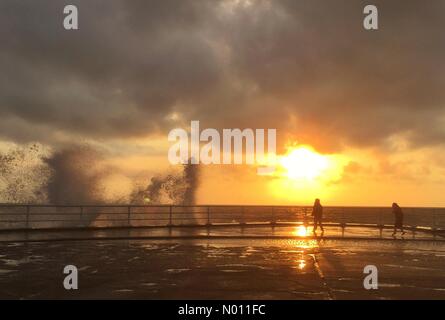 Aberystwyth Wales UK. Sunday 02 June 2019. Children silhouetted as they play in the spray of crashing waves on Aberystwyth promenade at sunset on a windy evening Credit: keith morris1/StockimoNews/Alamy Live News