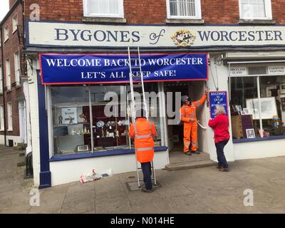 UK Coronavirus - Shops prepare to re-open - Worcester Worcestershire UK Saturday 10th April 2021 - A local shopkeeper adds a banner to her shop welcoming the return to business for non essential shops