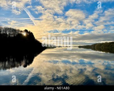 UK Weather: Sunny morning at Rivington. Cold sunny winter morning with sun and clouds reflected in Rivington reservoir near Chorley in Lancashire Stock Photo